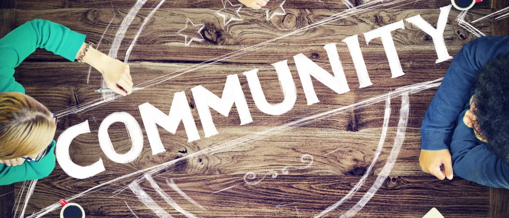 Word "community" surrounded by people's hands