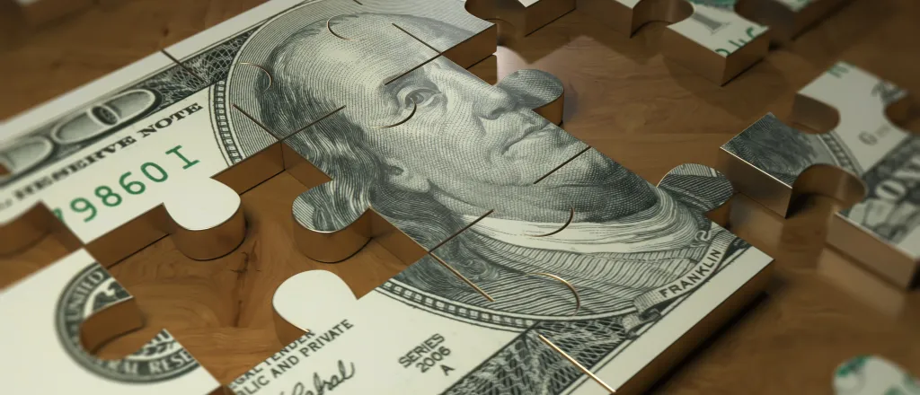 Metal puzzle of a United States one hundred dollar bill with pieces removed or missing.