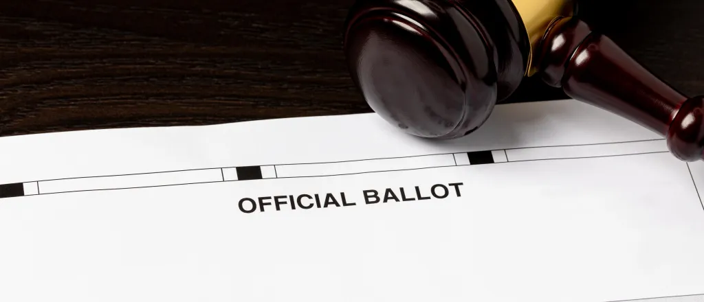 Court judge's gavel resting on an election ballot.